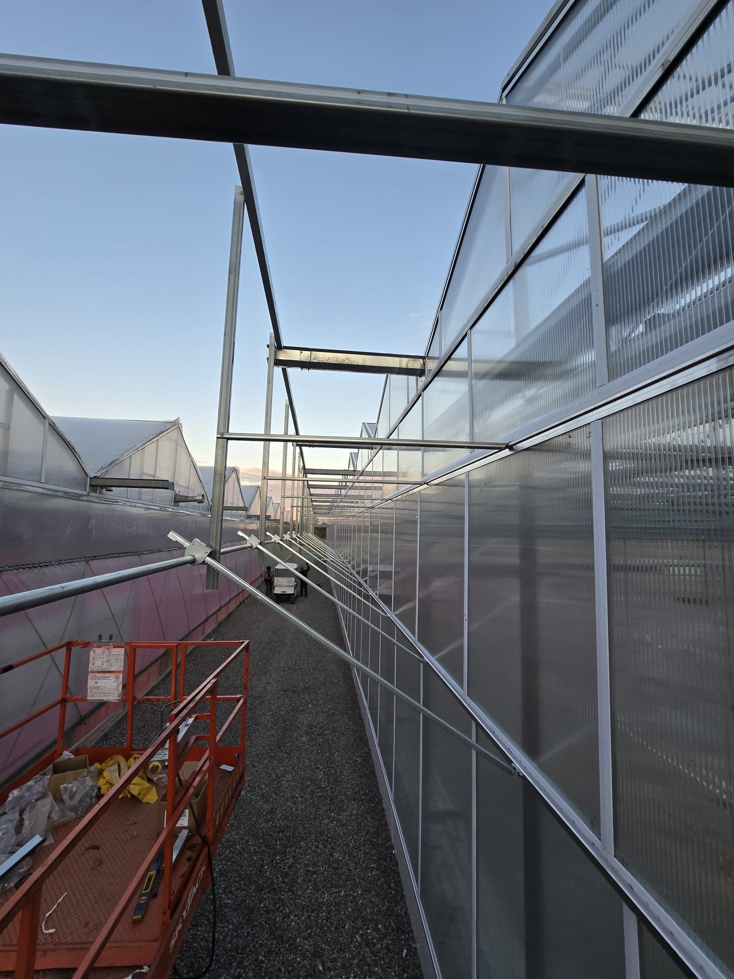 Greenways crew working along a commercial greenhouse structure at dusk