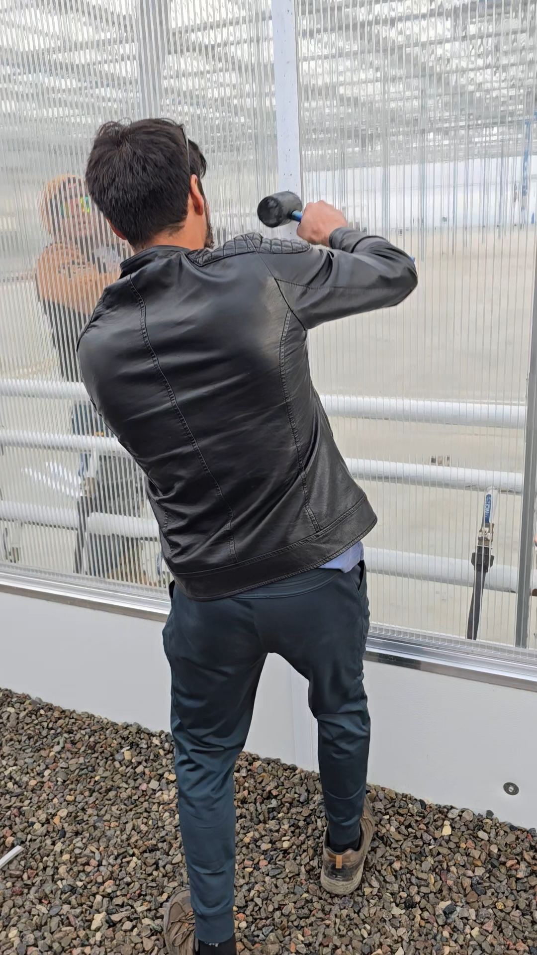 Technician installing polycarbonate panel on greenhouse wall