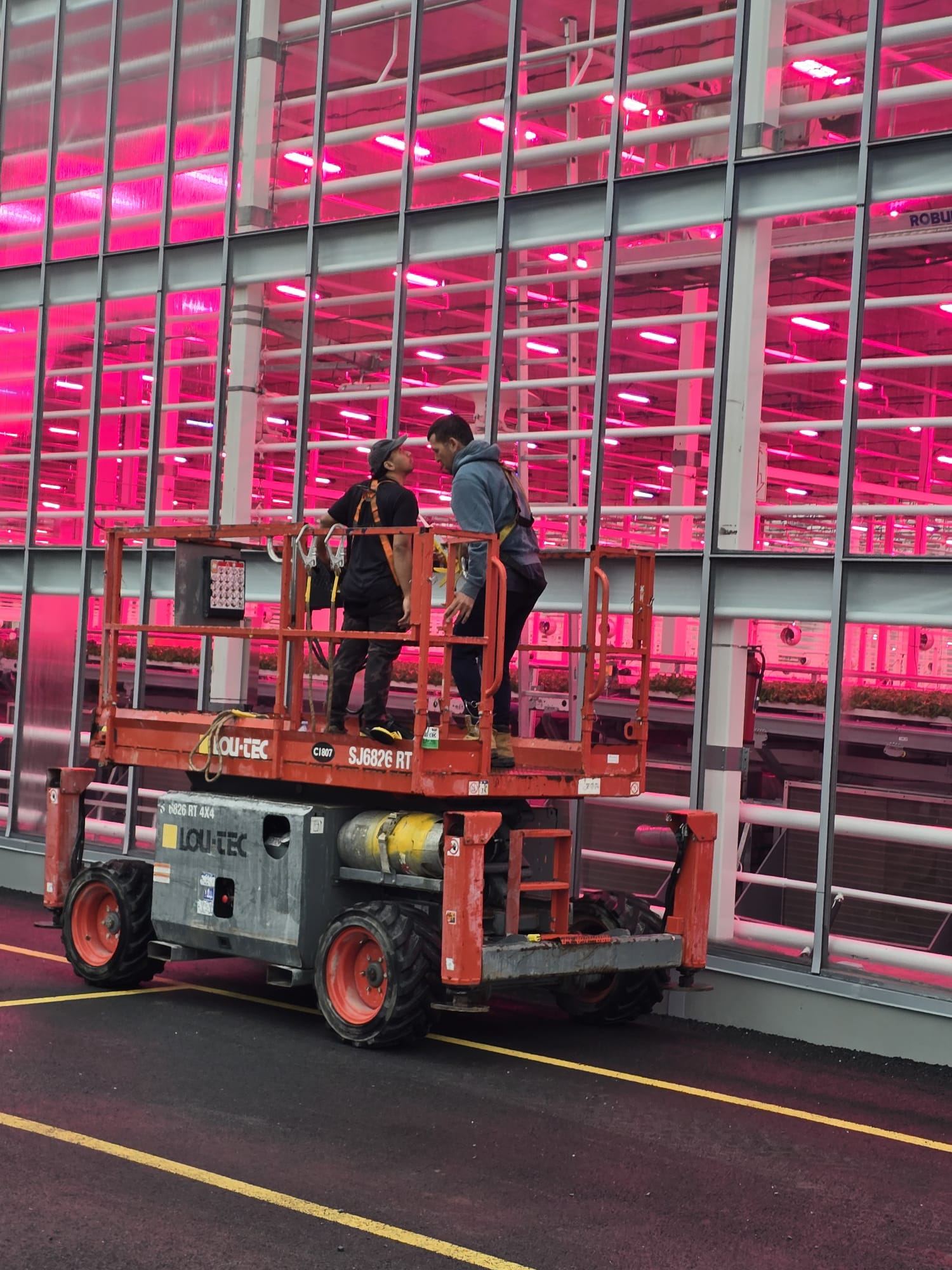 Crew on a scissor lift installing a shading system inside a greenhouse